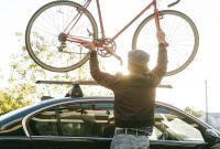 Persona subiendo una bicicleta al techo de un auto