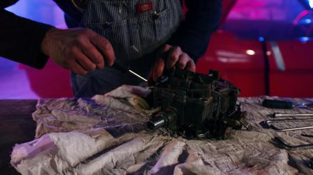 Pieza de un motor de auto siendo reparada con un desarmador sobre una mesa de un taller mecánico